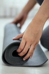 Crop female holding rolled mat on floor